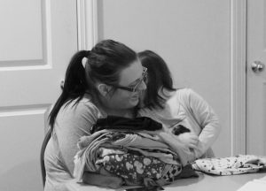 Elizabeth McVay and one of her daughters are pictured here. McVay is waiting for her laundry to be done in the room behind her.  